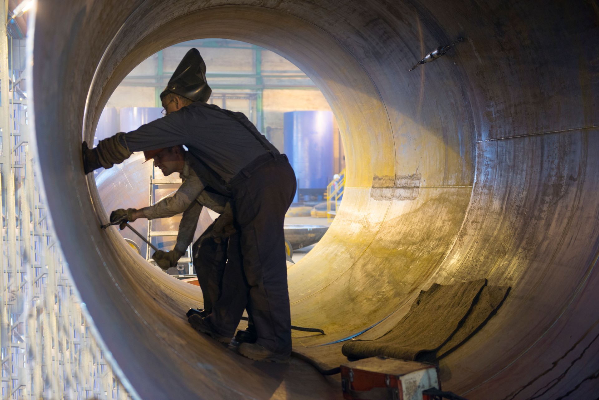Two welders work in a pipe for an oil pipeline.