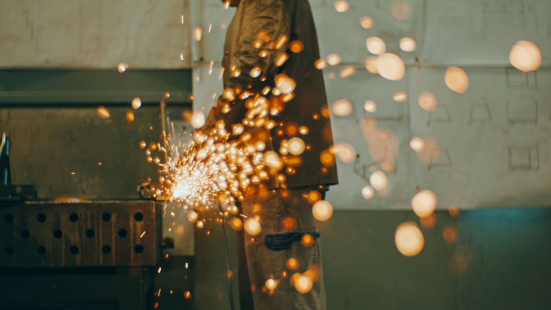 Worker using angle grinder in factory
